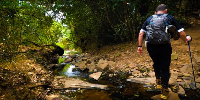 Hikers stepping over a stream at the Wolwespruit Trail Park 