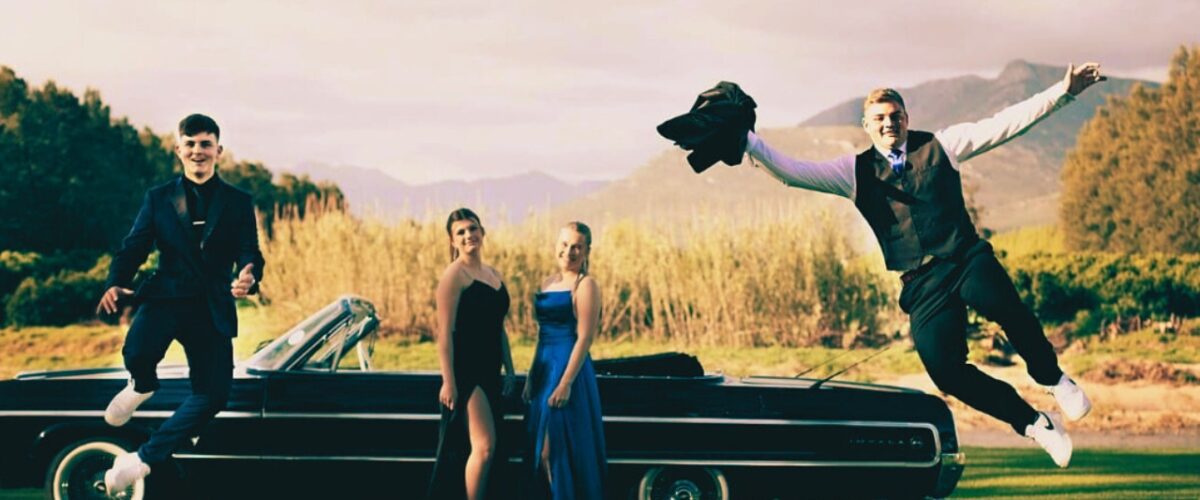Students exited around a vintage vehicle for matric farewell rides