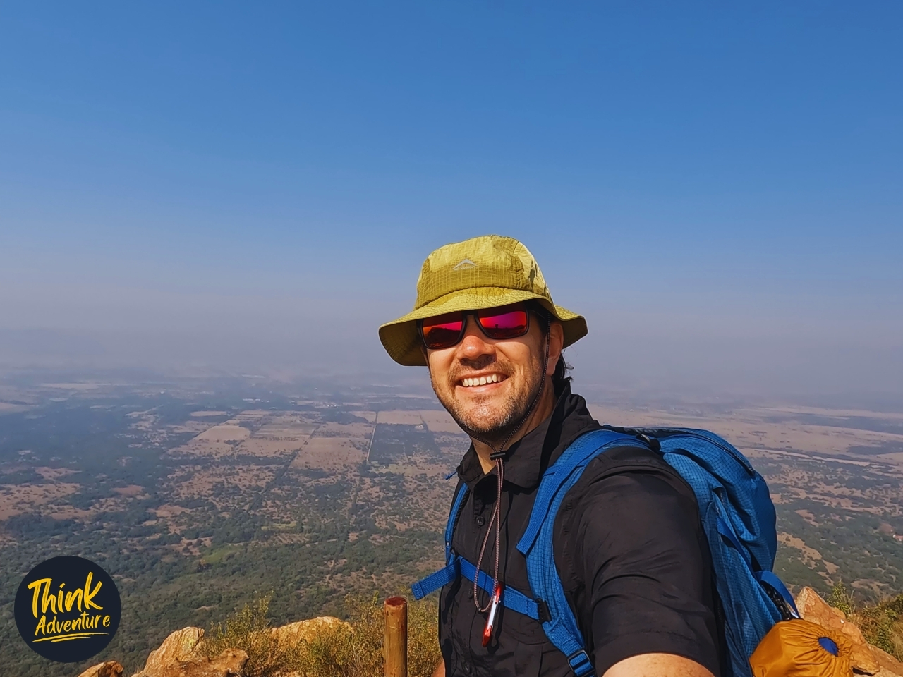 A hiker at the top of the Magaliesberg with the South of Magaliesberg as the backdrop on the Shelter Rock Hiking Trail