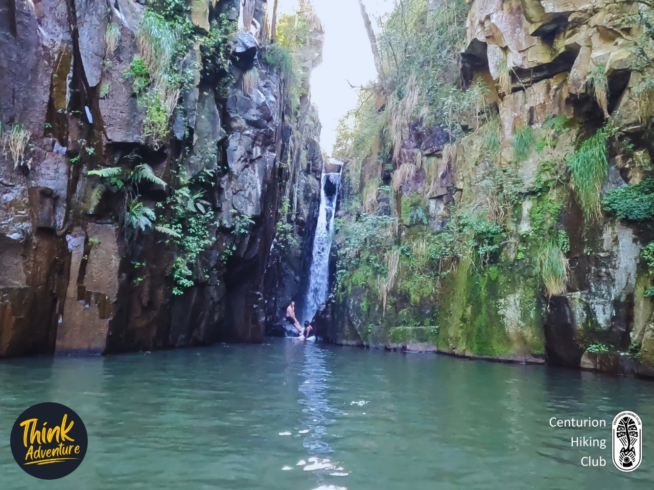 Narrow waterfall dropping between tall cliff walls into a large rock pool in Bald Ibis Gorge on the Bosbok Trail, Wathaba Hiking Trails