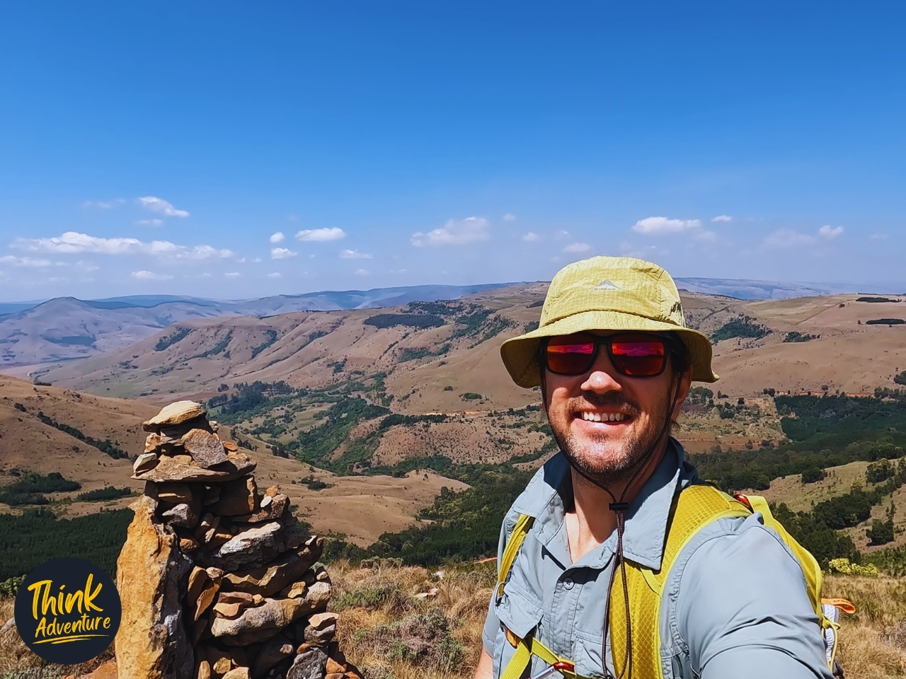 Shaun Douglas beside a stone cairn at the highest point of the Lynx Loop, overlooking the valley at Wathaba Hiking Trails